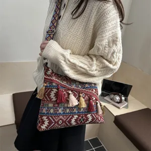 Ethnic style woven shoulder crossbody bag with colorful geometric strap and tassel decor.