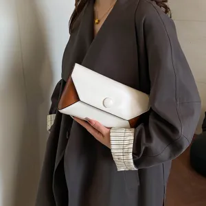Elegant color-block clutch bag detail view, envelope flap with round button, premium style