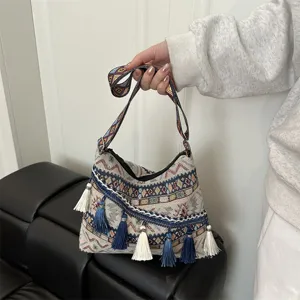 Close-up detail of ethnic woven shoulder bag with colorful tassels and geometric straps.