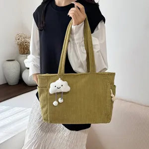 Detailed shot of a green corduroy tote bag featuring a cute cloud pendant for daily outfits.