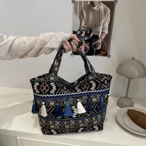 Woven tote bag detail showing ethnic embroidery texture, blue tassels, and sturdy handles.
