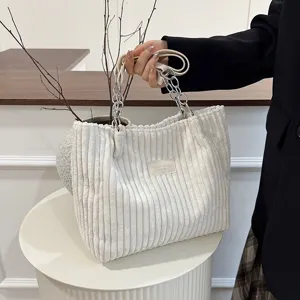 Close-up detail of white corduroy tote bag with metal chain handle, stylish daily commute style.