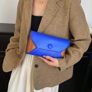 Color-blocked envelope clutch detail shot, showcasing blue and brown contrast design and shape.