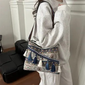 Detailed shot of bohemian ethnic style canvas shoulder bag with tassel charms and wide strap.
