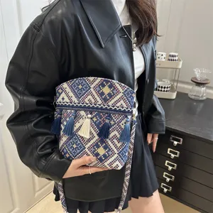 Vue détaillée d'un sac bandoulière tissé de style ethnique rétro avec des pompons.