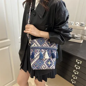 Sac à bandoulière tissé de style ethnique avec des pompons et un motif géométrique.