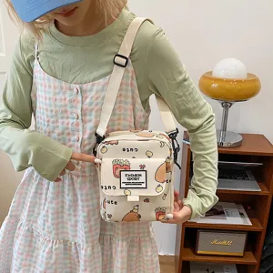 Canvas shoulder bag detail showing cute cartoon print, small pocket, and adjustable strap.