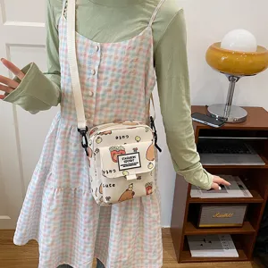 Cute canvas crossbody bag detail shot, featuring playful cartoon prints and front pocket design.