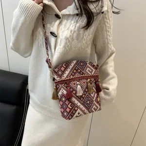 Vue détaillée du sac bandoulière tissé de style ethnique avec motifs colorés et charmants pompons.