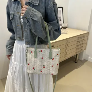 Summer travel woven tote bag featuring cute red embroidery, green handles and shoulder strap.