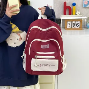 Detail view of the casual student backpack in wine red with front pockets and study text.