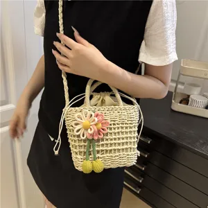 Detail view of woven straw bucket bag featuring cute flower decoration and drawstring.