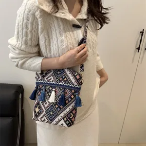 Sac bandoulière tissé de style ethnique avec motifs géométriques colorés et élégants pompons.