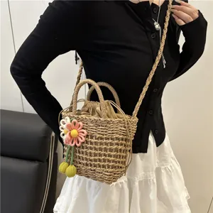 Detailed close-up of a handmade straw bucket bag featuring a cute knit flower and shoulder strap.
