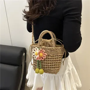 Detailed shot of the woven bucket bag featuring cute crochet flower charms and drawstring lining.