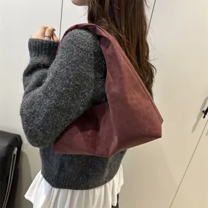 Close-up detail of the wine red leopard print shoulder bag worn casually by model indoors.