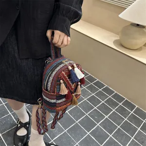 Detailed view of ethnic style woven mini backpack with colorful tassels and geometric patterns.