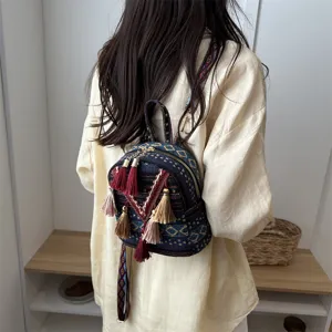 Detail view of the ethnic style woven mini backpack with colorful tassels and patterned strap.