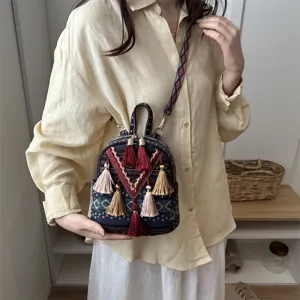 Detail view of ethnic style small backpack featuring colorful tassels and woven geometric patterns.