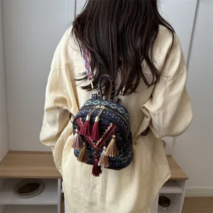 Ethnic style mini backpack featuring colorful tassels and geometric woven fabric details.