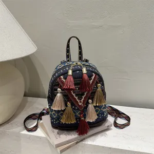 Detailed view of bohemian style woven mini backpack with colorful tassels and geometric straps.