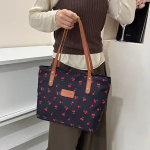 Detailed view of large capacity cherry print tote bag with brown leather handles for daily use.