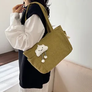 Detail view of the green corduroy tote bag featuring a cute cloud plush pendant and soft texture.