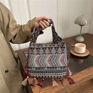 Borsa a tracolla tessuta in stile etnico bohémien con motivi geometrici e nappe colorate.