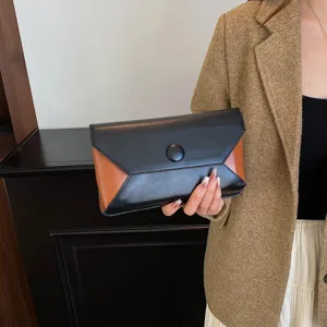 Detail view of stylish black and brown color block clutch bag, elegant design for evening.