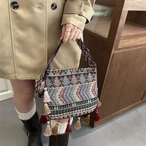 Dettaglio borsa a tracolla con nappe etniche, motivo geometrico tessuto colorato.