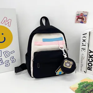 Children cartoon backpack detail view, black and white color block school bag with bear pendant.