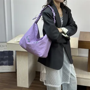 Detail view of purple shoulder tote bag with green letter print and stylish gathered strap.