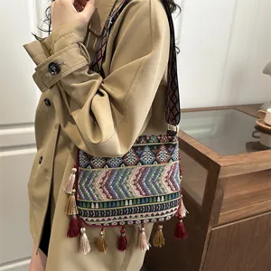 Borsa a tracolla ricamata in stile etnico con nappe colorate e larga tracolla tessuta.
