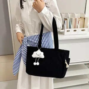 Close-up detail of black corduroy tote bag with cute plush cloud pendant, casual shoulder style.