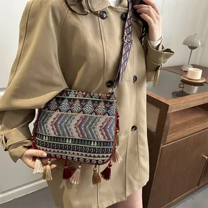 Vista dettagliata della borsa a tracolla etnica intrecciata con motivi geometrici e nappe.