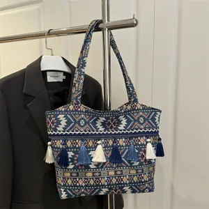 Detailed view of ethnic woven shoulder bag featuring intricate embroidery and hanging tassels.