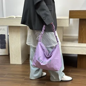 Detail view of casual light purple shoulder bag with scrunchie strap and letter print.