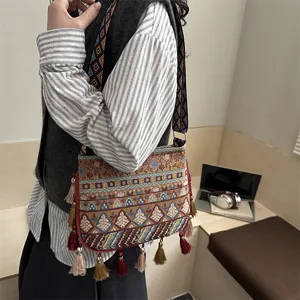 Borsa a tracolla tessuta in stile etnico con motivo geometrico e nappe colorate.
