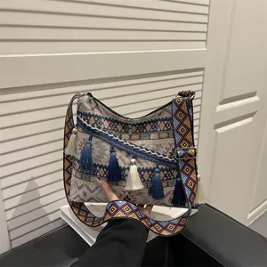 Ethnic style canvas crossbody bag with colorful geometric strap and tassel decor for women.