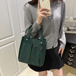 Grüne Canvas-Tragetasche mit mehreren Taschen für den Pendleralltag, lässig praktisch.