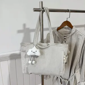 Corduroy tote bag detail showing fine texture, dual handles and cute cloud pendant.