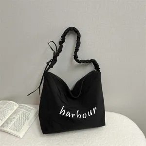 Black casual slouchy shoulder bag with white letter print, lightweight daily commuter tote bag.