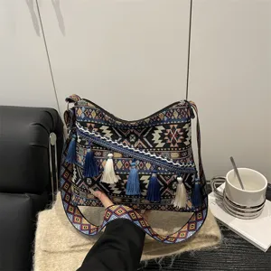 Ethnic style canvas shoulder bag with geometric patterns, tassels and wide strap.