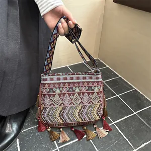 Borsa a tracolla tessuta in stile etnico con nappe colorate e ampia tracolla geometrica.