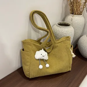 Detailed view of the stylish corduroy tote bag in a cozy lifestyle setting with cute pendant.