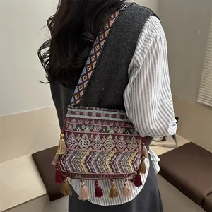 Primo piano dettagliato della borsa a tracolla etnica con tracolla tessuta e nappe colorate.