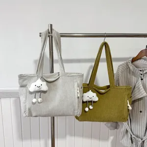 Detail close-up view of casual corduroy tote bags hanging on rack with cute cloud charms.