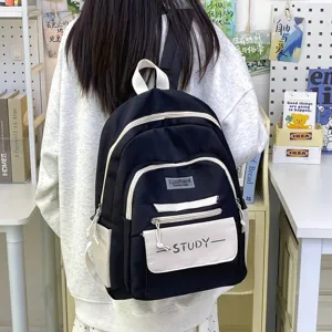 Detailed shot of a black canvas student backpack with front pocket and contrast trim.