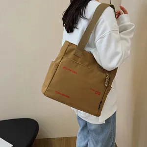 Detailed view of the brown canvas tote bag featuring stylish red embroidery and large capacity.