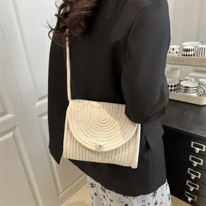 Detailed view of handmade woven envelope shoulder bag with elegant pearl button and chic strap.